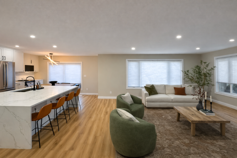 White cellular shades on large living room window with cream sofa and green armchairs - Bold Blinds Edmonton